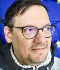 Eine Portraitaufnahme von Erich Adam vor einer Europafahne